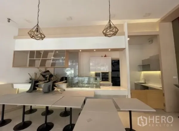 零售空间 出租在Khlong Toei, Bangkok - 前台服务区带展示冷柜、置物架与吊灯。