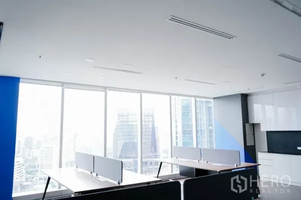 Office Space for rent in Khlong Toei, Bangkok - Workstations beside panoramic windows and built-in pantry cabinets overlooking city towers.