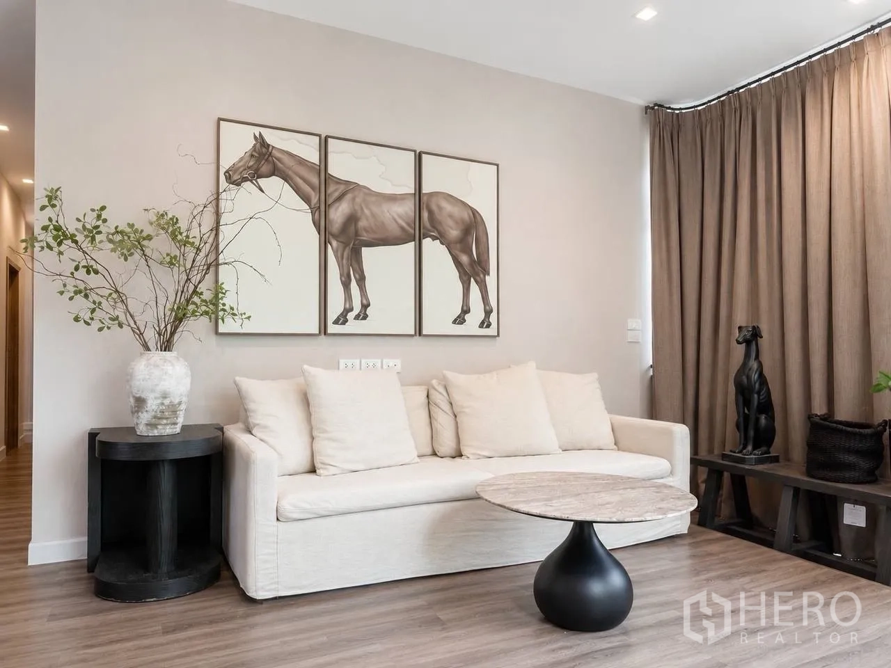 บ้านเดี่ยว for sale in Bang Kruai, Nonthaburi - ห้องนั่งเล่นสไตล์โมเดิร์น โซฟาสีครีม ภาพม้าติดผนัง และโต๊ะกลางทรงกลม