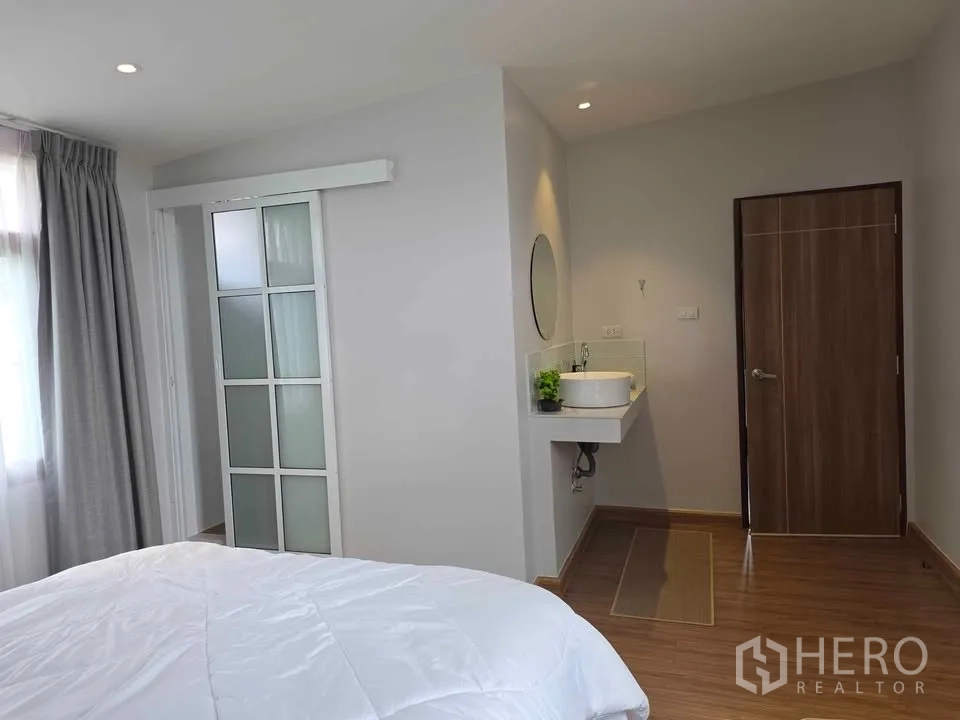 บ้าน ให้เช่าในKhlong Toei, Bangkok - ห้องนอนมีอ่างล้างหน้า ประตูบานเลื่อนกระจกฝ้าสู่ห้องน้ำ และพื้นไม้