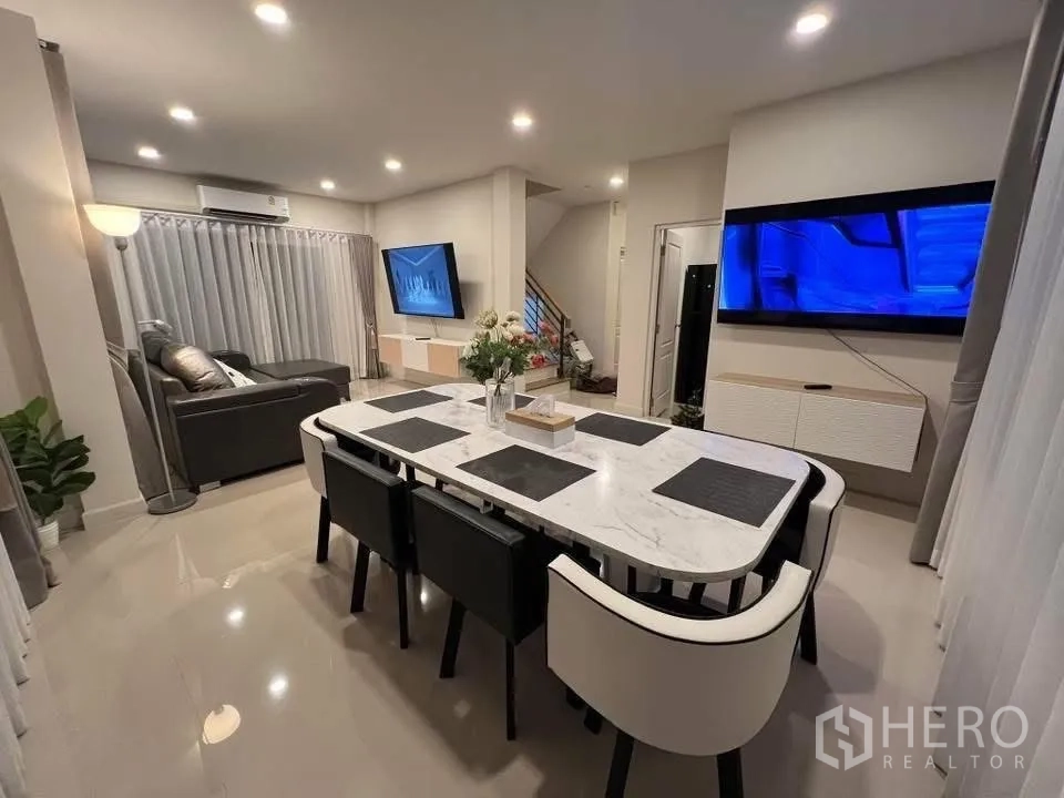 บ้านเดี่ยว for rent in Prawet, Bangkok - พื้นที่รับประทานอาหารแบบเปิดพร้อมโต๊ะหินอ่อน เก้าอี้หกตัว และผนังทีวี.