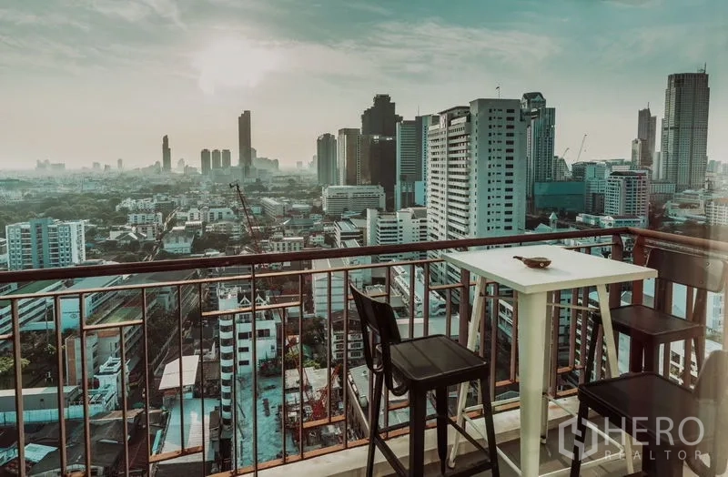 Condominium for rent in Sathon, Bangkok - Private balcony with bar table and chairs overlooking the Bangkok skyline at sunset.