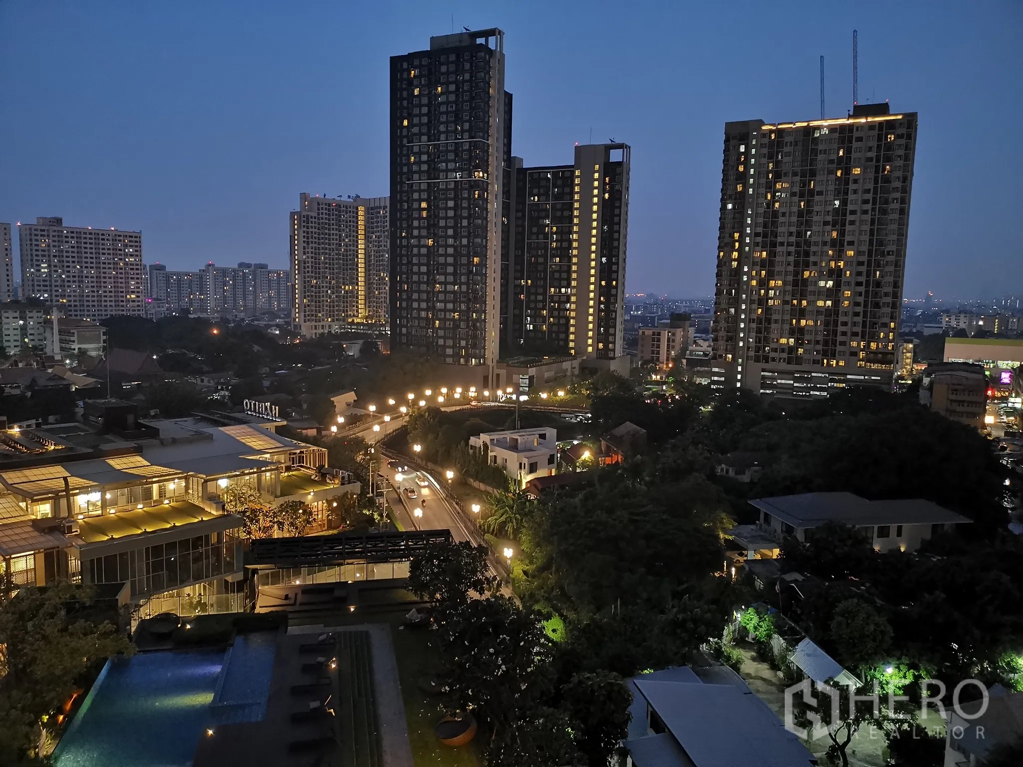 公寓 出租或出售在Watthana, Bangkok - 夜景视角，可见点亮的泳池与多栋高楼。