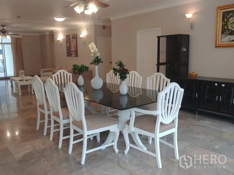 公寓 出租或出售在Watthana, Bangkok - 明亮的餐区，玻璃餐桌与白色餐椅，铺大理石地面，旁连客厅。