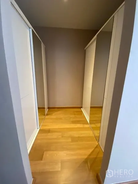 Detached House for rent in Huai Khwang, Bangkok - Walk-in closet corridor with mirrored wardrobes and wooden flooring.