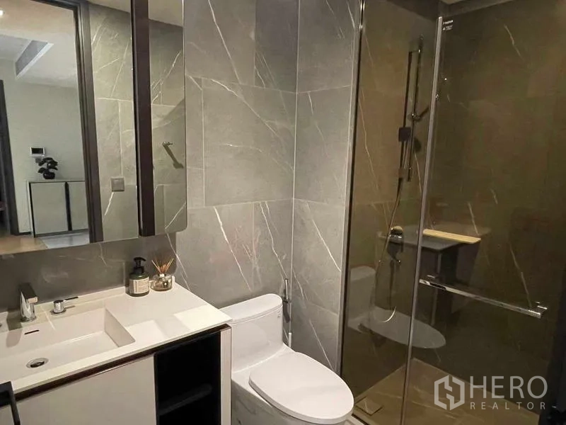 Condominium for rent - Guest bathroom with glass-enclosed shower, vanity and toilet.