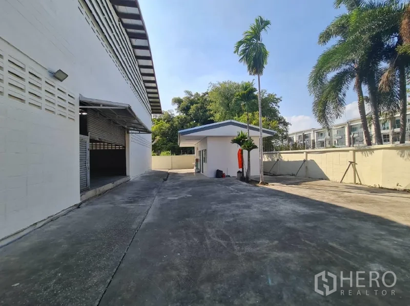 Warehouse for rent in Khlong Toei, Bangkok - Driveway around the building with a small guardhouse and palms.