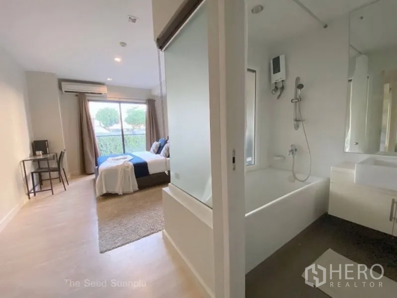 Condominium for rent or sale in Sathon, Bangkok - Second bedroom with work desk and adjacent bathroom featuring a bathtub and glass partition.