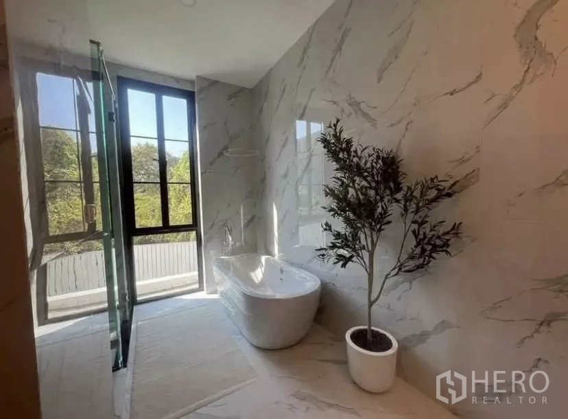 独立式住宅 出租在Lat Phrao, Bangkok - 浴室配独立浴缸、仿大理石墙面与采光窗。