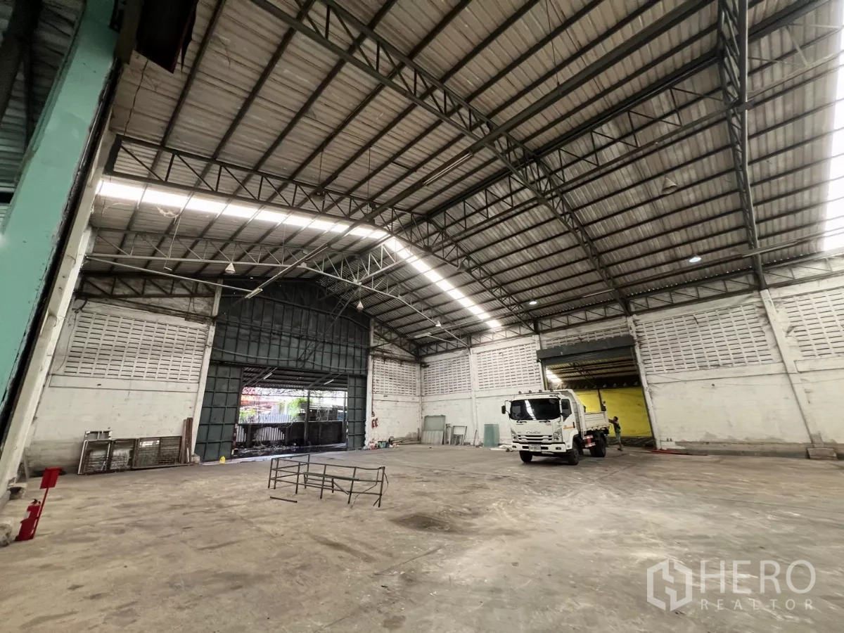 Warehouse for rent in Khlong Sam Wa, Bangkok - High‑ceiling warehouse interior with wide entry door and maneuvering space for trucks.