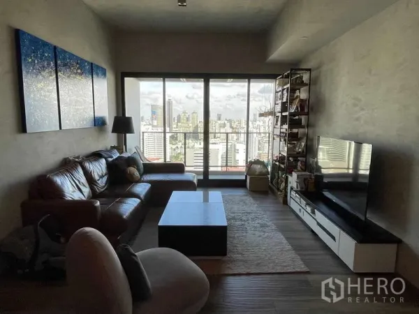 Condominium for rent or sale in Watthana, Bangkok - Living area facing sliding glass doors to balcony with expansive Bangkok skyline.