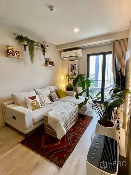 คอนโด ขาย - ห้องนั่งเล่นสว่าง โซฟาสีขาว ต้นไม้ในห้อง พร้อมระเบียงวิวเมือง ที่ The Tree พัฒนาการ-เอกมัย