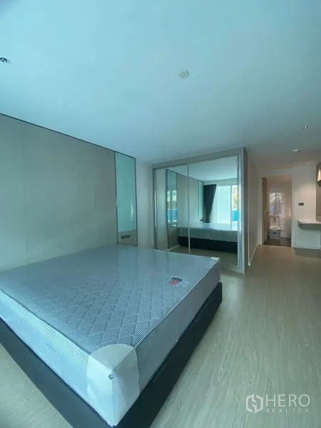 อพาร์ทเมนท์ ให้เช่าในWatthana, Bangkok - ห้องนอนหลักพร้อมเตียงขนาดใหญ่ ตู้เสื้อผ้าบานกระจก และทางเข้าห้องน้ำในตัว พื้นไม้โทนอ่อน