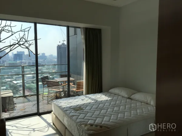 Condominium for rent in Sathon, Bangkok - Master bedroom with floor-to-ceiling windows opening to a balcony and Bangkok city view.