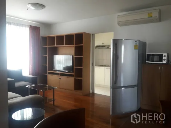 คอนโด ให้เช่าในKhlong Toei, Bangkok - ห้องนั่งเล่นอบอุ่น ชั้นวางทีวีและชั้นบิลท์อิน โซฟา ชุดโต๊ะกลางกระจก และหน้าต่างใหญ่ติดครัว