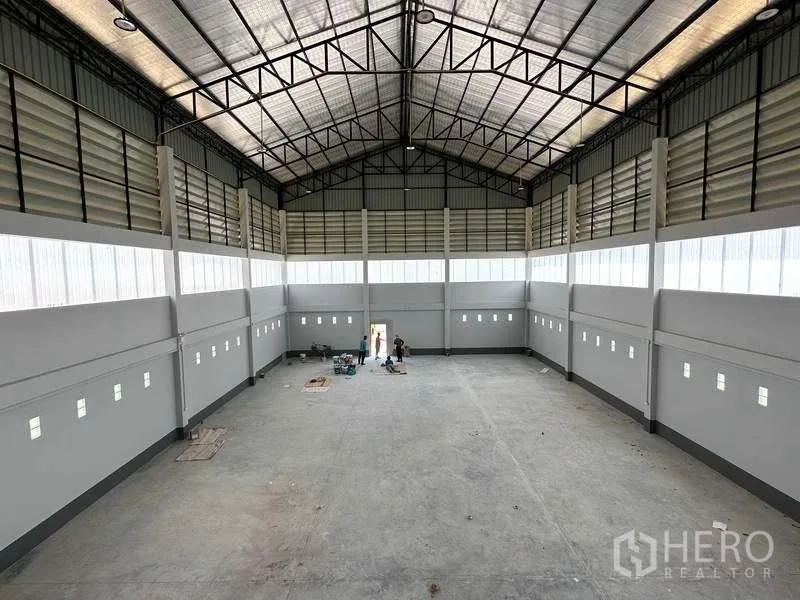 Factory for sale in Khlong Luang, Pathum Thani - View from mezzanine over the spacious production area with steel truss ceiling and side windows.