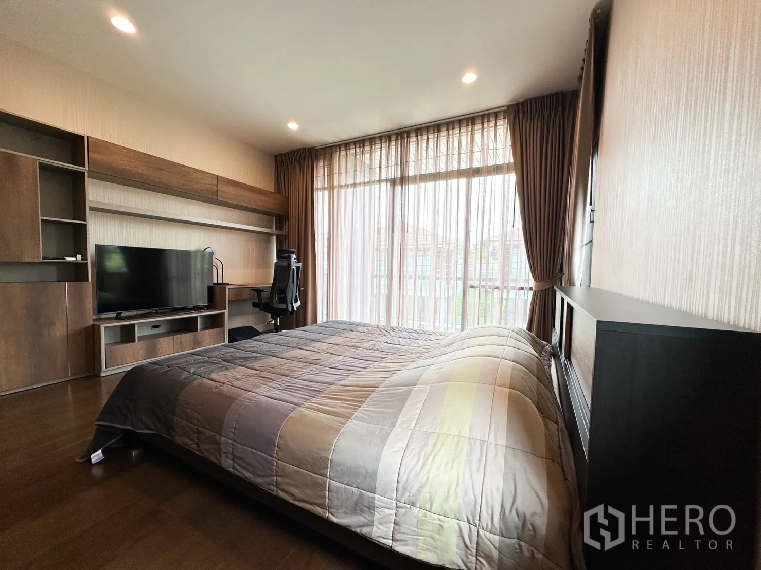 Detached House for rent or sale in Bang Kapi, Bangkok - Master bedroom angle with built-in TV unit, study desk and balcony glazing.