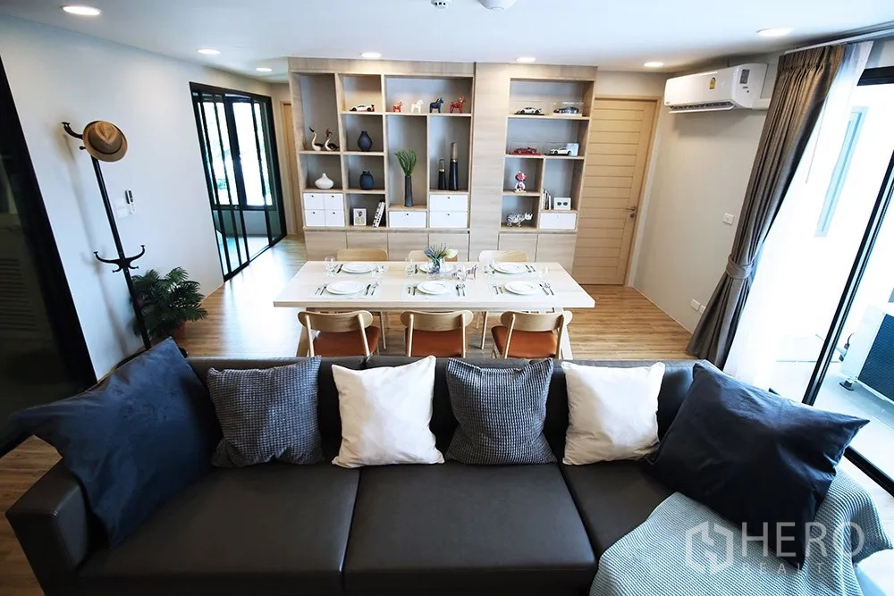 Condominium for rent in Watthana, Bangkok - Open-plan living and dining area with a table set for six and full-height display shelving.