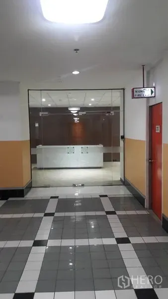 办公空间 出租在Huai Khwang, Bangkok - 通往玻璃门入口和前台的办公走廊，地面为瓷砖，位于曼谷Huai Khwang。
