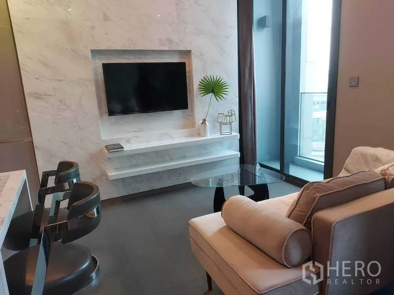 คอนโด ให้เช่าในHuai Khwang, Bangkok - มุมนั่งเล่นผนังทีวีหินอ่อน โซฟา และประตูกระจกเปิดสู่ระเบียง