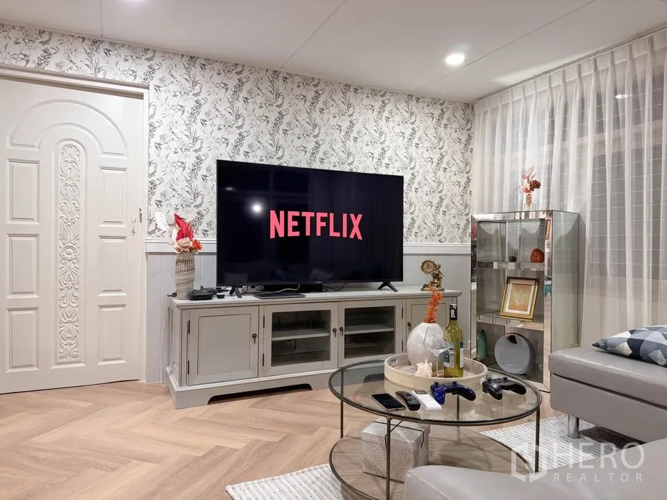 บ้าน ให้เช่าในHuai Khwang, Bangkok - ห้องนั่งเล่นพร้อมทีวีจอใหญ่และผนังลายดอกไม้.