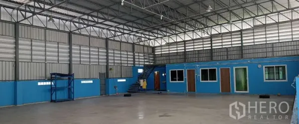 Warehouse for rent in Mueang Samut Sakhon, Samut Sakhon - Open floor warehouse with mezzanine walkway, internal office rooms and stair access beneath a metal roof.