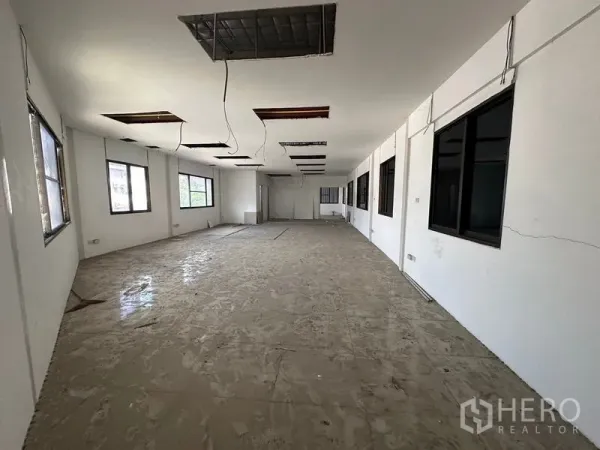 Warehouse for rent in Suan Luang, Bangkok - Large unfinished office floor inside the warehouse with multiple windows and ceiling openings.