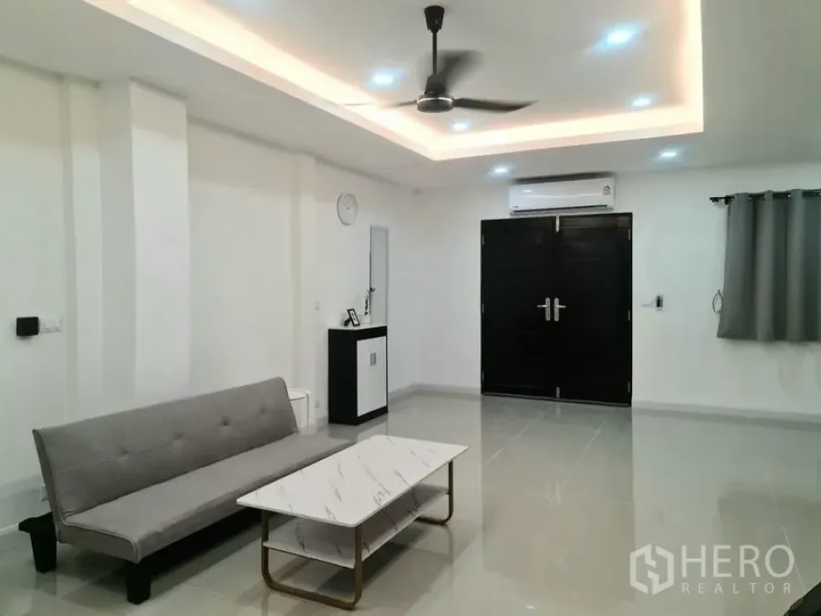 ทาวน์เฮาส์ ให้เช่าในKhlong Toei, Bangkok - ห้องนั่งเล่นสว่าง โซฟาสีเทา โต๊ะกลางหินอ่อน เพดานซ่อนไฟ พัดลมติดเพดาน แอร์ และประตูสีเข้ม