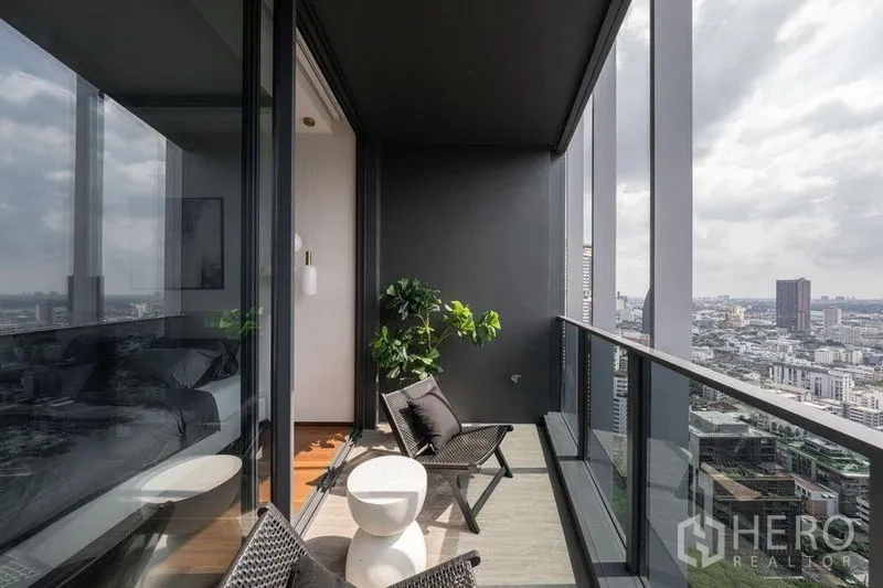 公寓 出租在Khlong Toei, Bangkok - 半室外阳台，躺椅与小圆桌，玻璃护栏眺望曼谷城景。