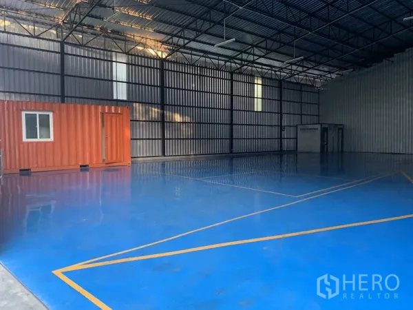 货栈 出租在Khan Na Yao, Bangkok - 蓝色环氧地坪的开阔储存区，仓内配有橙色集装箱式办公室。