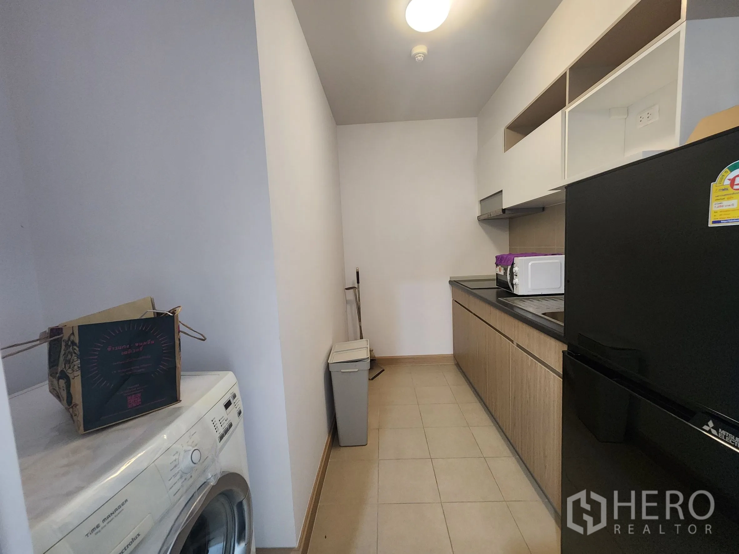 คอนโด for rent in Huai Khwang, Bangkok - ครัวแบบแกลเลย์ พร้อมตู้เก็บของ เตา ไมโครเวฟ ตู้เย็น และเครื่องซักผ้า