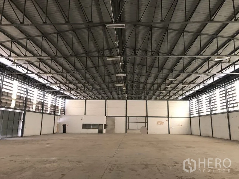 货栈 出租在Khlong Luang, Pathum Thani - 仓库内部，高挑钢桁架屋顶与百叶通风，角落设有小型办公室。