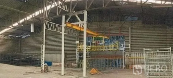Warehouse for rent in Phra Pradaeng, Samut Prakan - Industrial bay with steel framing and equipment area beneath a high roof.