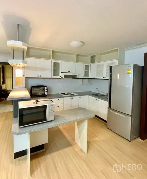 คอนโด ให้เช่าหรือขายในWatthana, Bangkok - ครัวบิวท์อินตู้สีขาว พร้อมเตาไฟฟ้า เครื่องดูดควัน ตู้เย็น และไมโครเวฟ