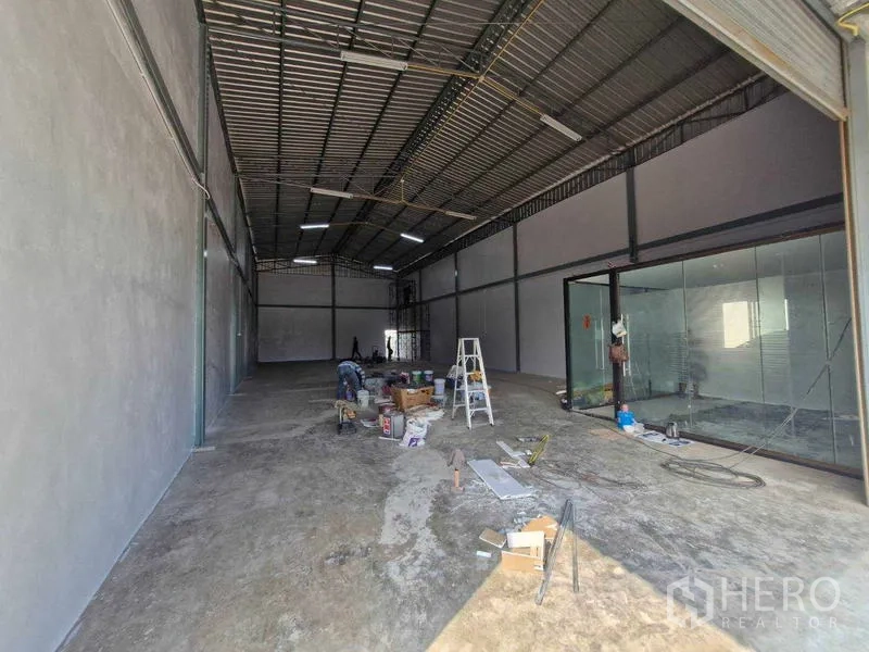 Warehouse for rent in Bang Khun Thian, Bangkok - Spacious warehouse interior with high steel roof, concrete floor, and a glass-partitioned office.