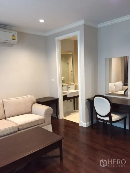 คอนโด ขายในHuai Khwang, Bangkok - มุมนั่งเล่นอบอุ่นพร้อมโซฟา โต๊ะเครื่องแป้ง และประตูทางเข้าห้องน้ำปูกระเบื้อง