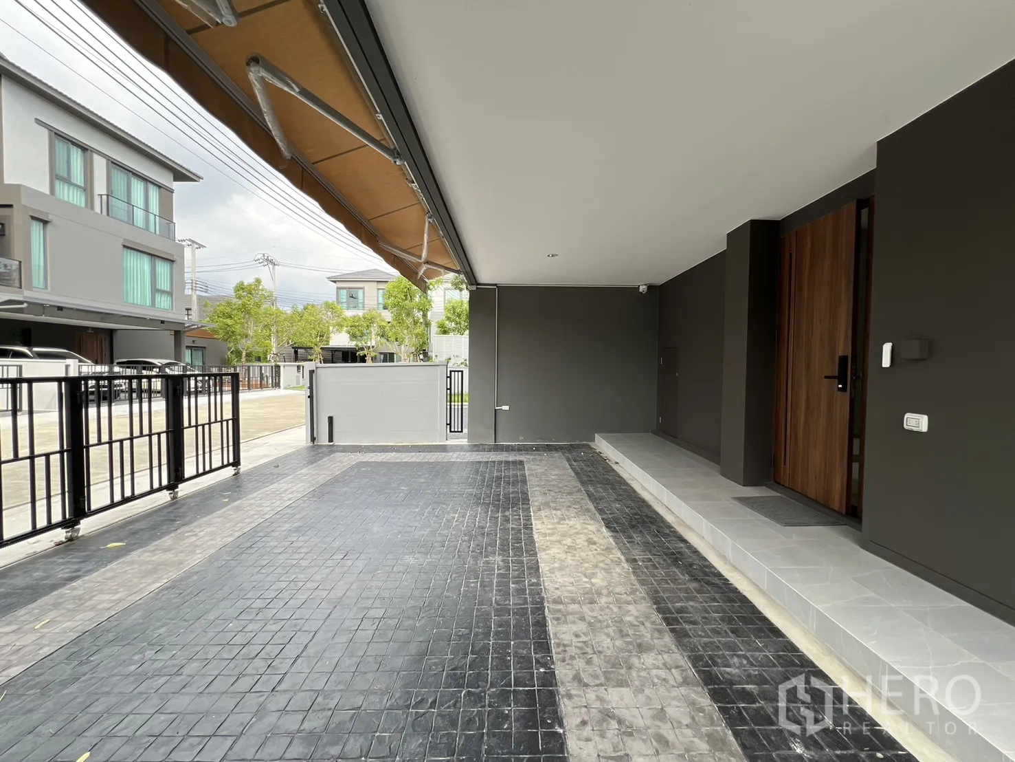 Detached House for rent in Prawet, Bangkok - Spacious carport facing quiet estate street with metal fence.