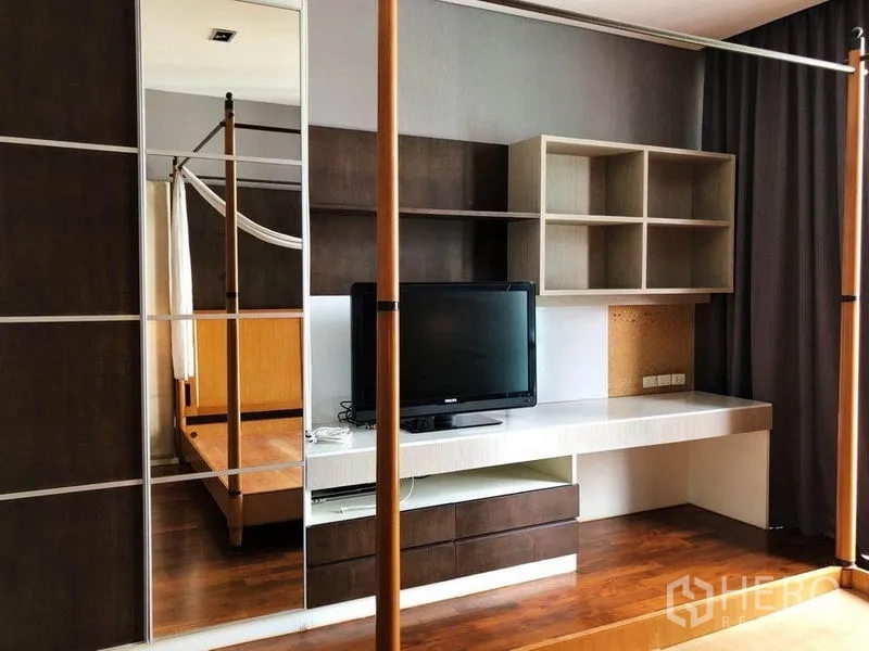 คอนโด ให้เช่าในKhlong Toei, Bangkok - มุมห้องนอนใหญ่พร้อมโต๊ะทำงาน ชั้นวางของ ทีวี และตู้เสื้อผ้าบานกระจก ใกล้เตียงสี่เสา