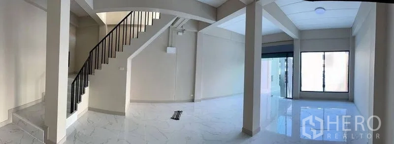 Shophouse for rent in Bang Kapi, Bangkok - Open-plan interior featuring a staircase and a glass storefront entrance.