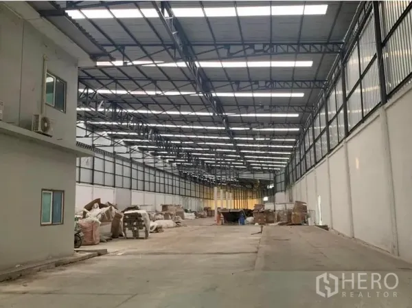 货栈 出租在Nakhon Pathom - 仓库另一视角，可见侧边办公室、屋顶采光与笔直宽敞的车辆通道。