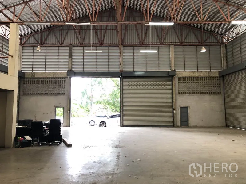 货栈 出租在Khlong Sam Wa, Bangkok - 从仓库内朝入口望去，两扇高卷闸门与宽装卸区，可见外部车辆。