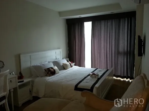 คอนโด ให้เช่าในWatthana, Bangkok - ห้องนอนหลักสว่าง โทนขาว มีเตียง โต๊ะทำงาน และผ้าม่านทึบสูงจรดเพดาน