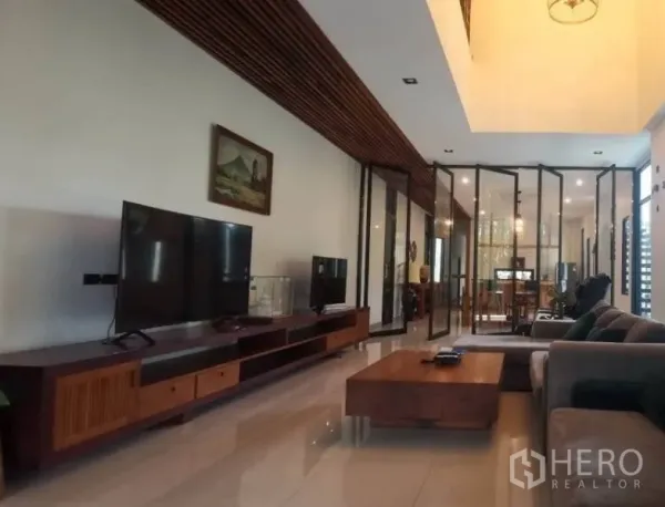 独立式住宅 出售在Pak Kret, Nonthaburi - 开放式客厅，木质电视柜、亮面地砖与玻璃隔断。