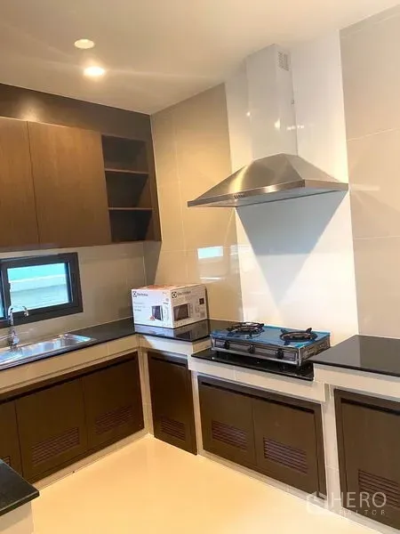 独立式住宅 出租在Saphan Sung, Bangkok - U形厨房，燃气灶、不锈钢烟机、水槽与木质柜体。