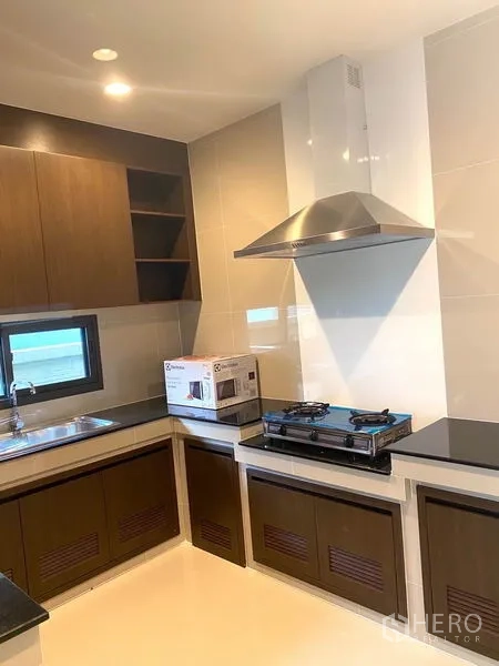 独立式住宅 出租在Saphan Sung, Bangkok - U形厨房，燃气灶、不锈钢烟机、水槽与木质柜体。