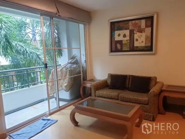 คอนโด ให้เช่าในWatthana, Bangkok - ห้องนั่งเล่นกะทัดรัด โซฟาและโต๊ะกลางกระจก ข้างประตูบานเลื่อนออกระเบียง