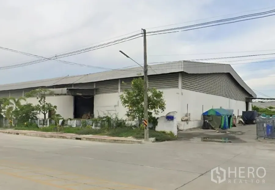 Warehouse for rent in Bang Pakong, Chachoengsao - Corner exterior of the warehouse with fenced greenery, service yard and roadside frontage.