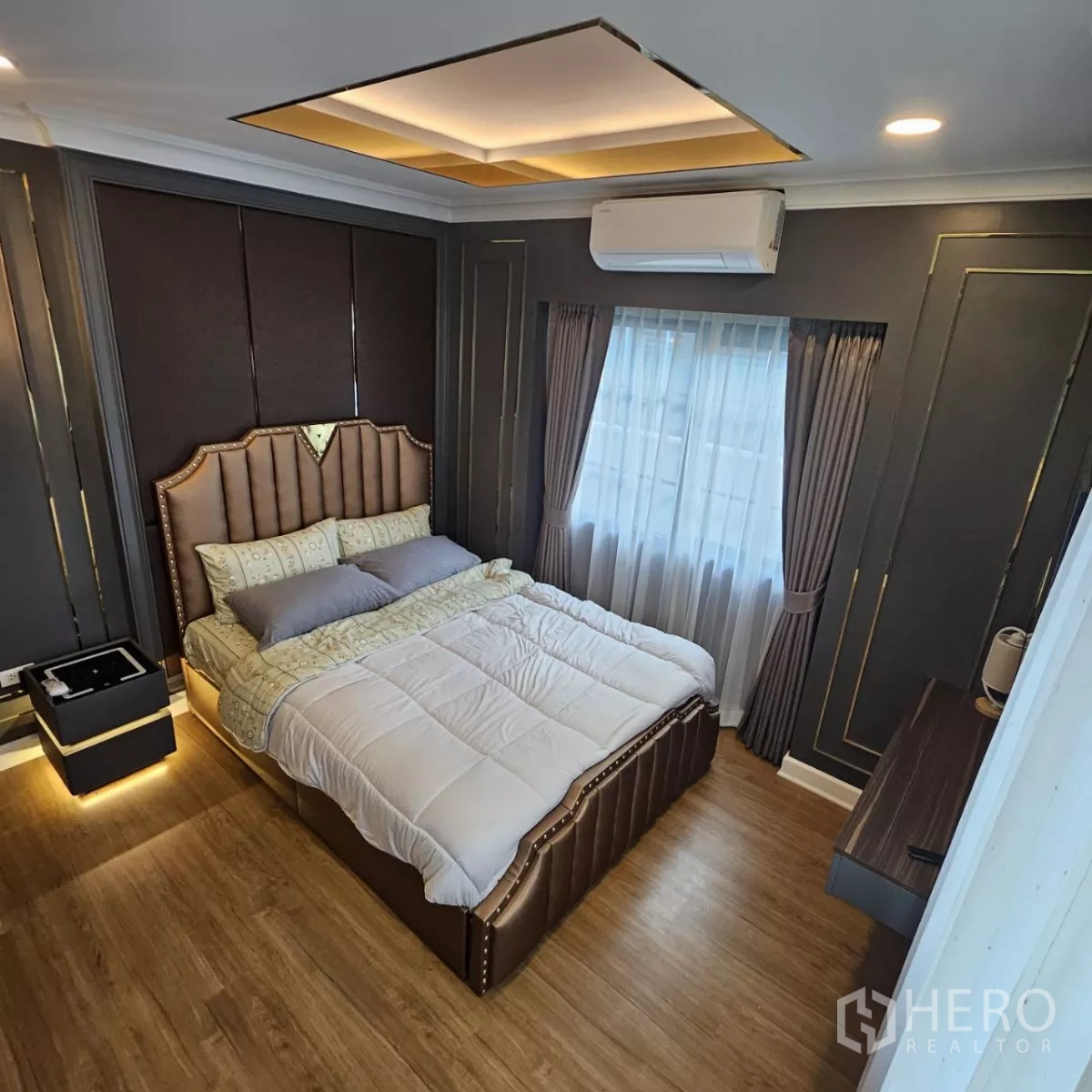 Detached House for rent in Bang Phli, Samut Prakan - Stylish bedroom with padded headboard, paneled dark walls, curtained window and wood flooring.