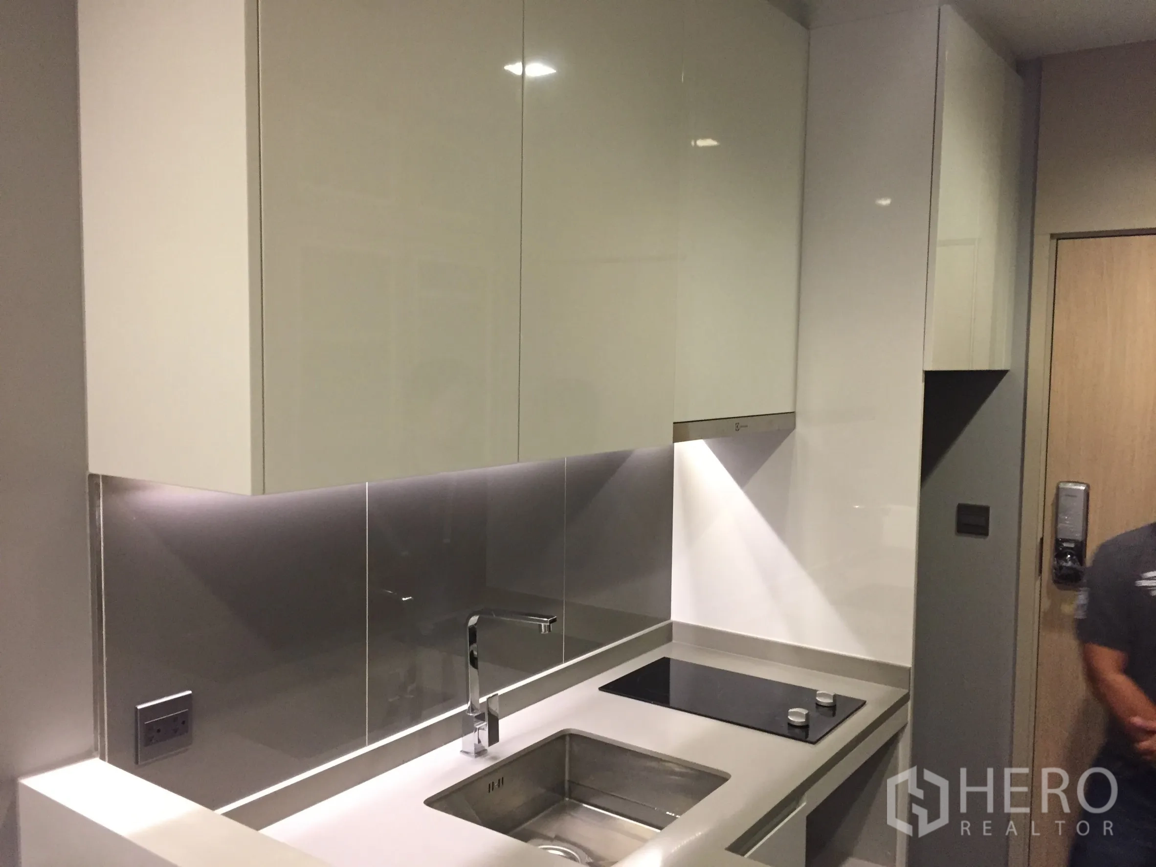 公寓 出租在Watthana, Bangkok - 一字型厨房，白色亮面橱柜、不锈钢挡板与水槽。