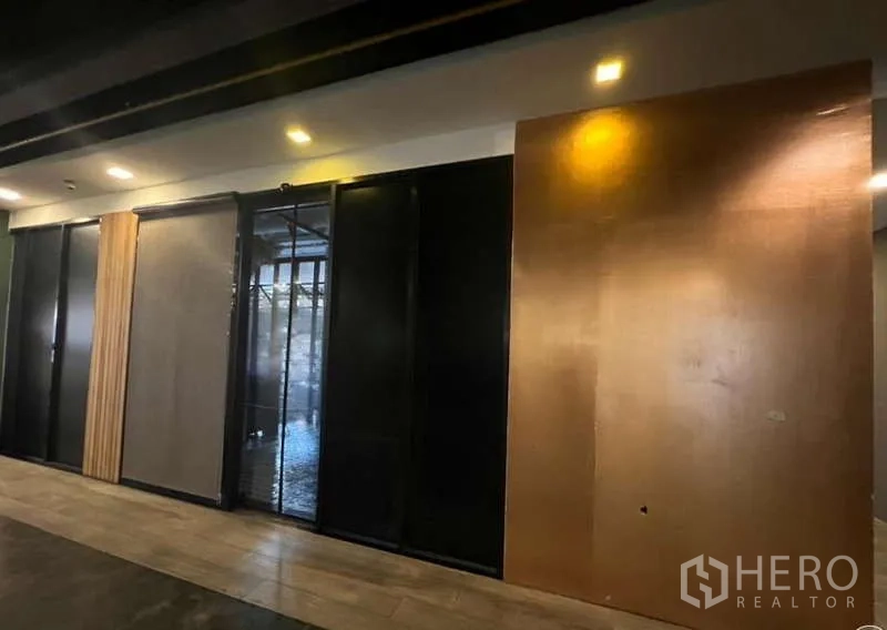 零售空间 出租在Watthana, Bangkok - 室内墙面采用深色推拉面板与嵌入式射灯。